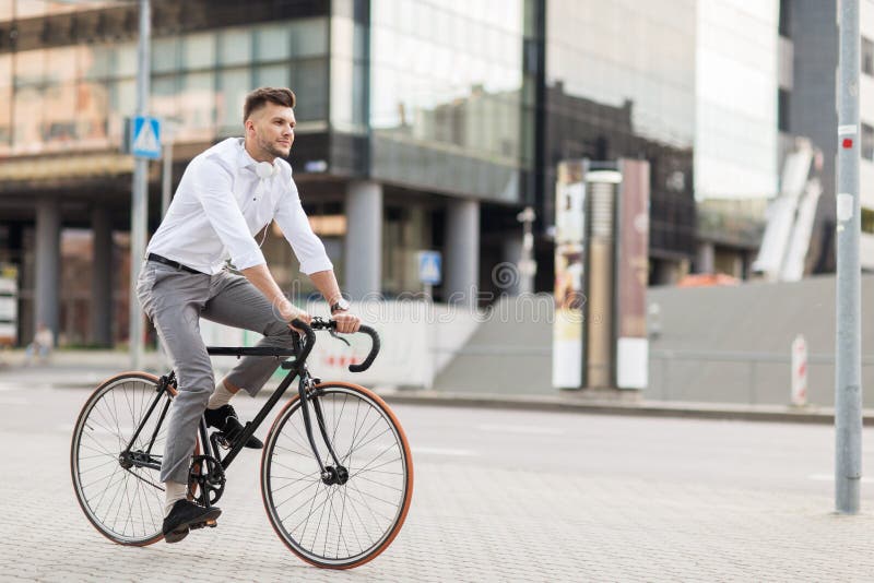 Homem com os fones de ouvido que montam a bicicleta na rua da cidade foto de stock royalty free Homem com os fones de ouvido que montam a bicicleta na rua da cidade foto de stock royalty free
