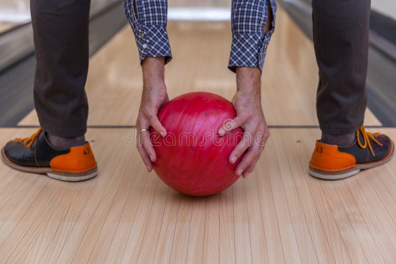 Homem com uma bola de rolamento que joga o boliches em uma pista de boliches no centro de esportes imagem de stock Homem com uma bola de rolamento que joga o boliches em uma pista de boliches no centro de esportes imagem de stock