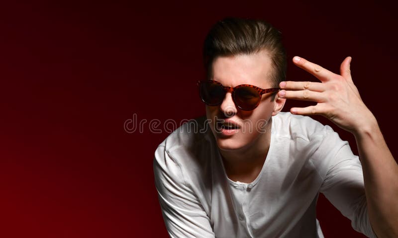 Homem consider?vel novo elegante no vestido ocasional e em ?culos de sol elegantes no est?dio em um fundo vermelho fotos de stock royalty free Homem consider?vel novo elegante no vestido ocasional e em ?culos de sol elegantes no est?dio em um fundo vermelho fotos de stock royalty free