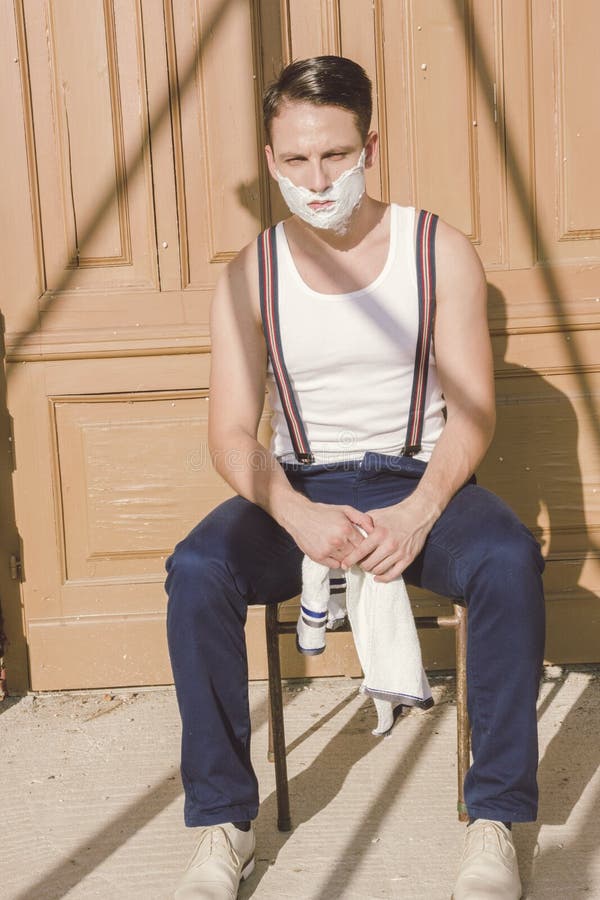 Homem considerável com rapagem da espuma em sua cara e da toalha em torno do seu imagens de stock royalty free Homem considerável com rapagem da espuma em sua cara e da toalha em torno do seu imagens de stock royalty free