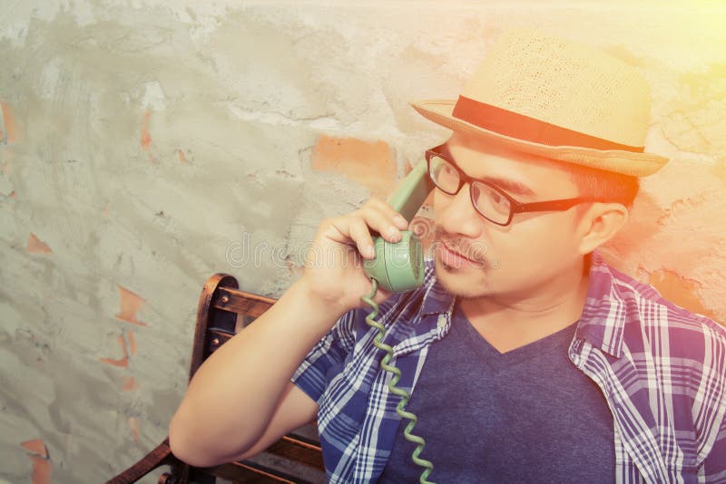 Homem considerável do moderno que fala com o telefone retro no tijolo foto de stock Homem considerável do moderno que fala com o telefone retro no tijolo foto de stock