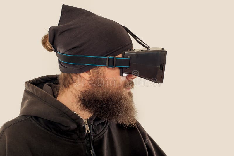 Homem considerável farpado novo que usa o dispositivo da realidade virtual foto de stock royalty free Homem considerável farpado novo que usa o dispositivo da realidade virtual foto de stock royalty free