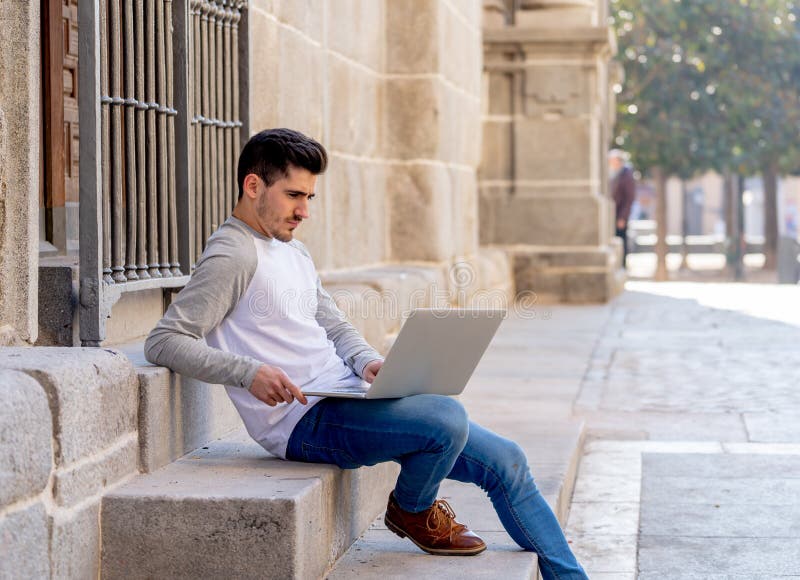 Homem considerável novo que trabalha e que estuda no portátil em um europeu imagem de stock royalty free Homem considerável novo que trabalha e que estuda no portátil em um europeu imagem de stock royalty free