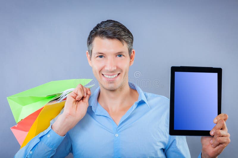 Man with shopping bags smiling with tablet ad. Man with shopping bags smiling with tablet ad