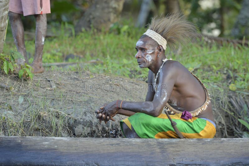 YOUW VILLAGE, ATSY DISTRICT, ASMAT, NEW GUINEA, INDONESIA - MAY 23: Headhunter of a tribe of Asmat. Traditional facepainting and headdress. May 23, 2013, Youw Village, Irian Jaya province, Indonesia. YOUW VILLAGE, ATSY DISTRICT, ASMAT, NEW GUINEA, INDONESIA - MAY 23: Headhunter of a tribe of Asmat. Traditional facepainting and headdress. May 23, 2013, Youw Village, Irian Jaya province, Indonesia