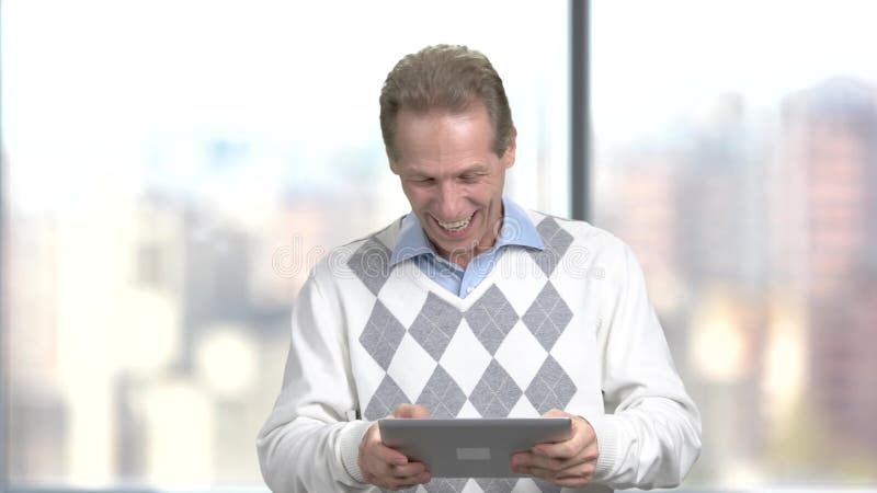 Homem de meia idade engraçado que joga na tabuleta digital
