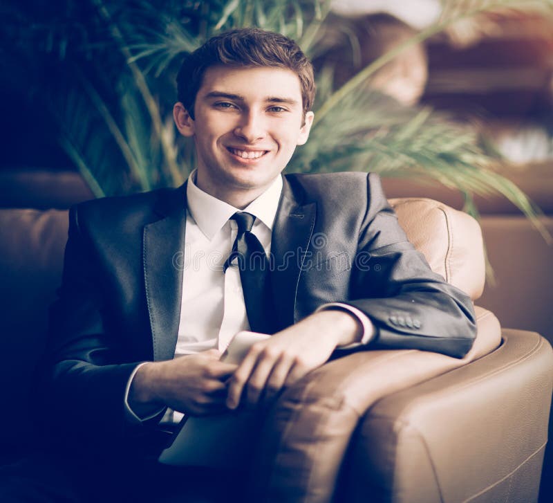 Homem de neg?cios relaxado que senta-se na frente de Windows do offic fotografia de stock Homem de neg?cios relaxado que senta-se na frente de Windows do offic fotografia de stock