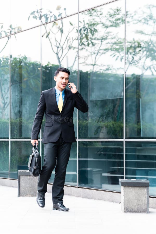 Homem de negócio asiático que fala ao telefone celular fora fotos de stock Homem de negócio asiático que fala ao telefone celular fora fotos de stock
