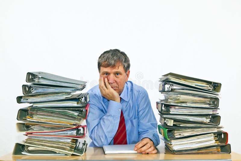 Homem de negócio com as pilhas de pastas de anel em sua mesa imagem de stock royalty free Homem de negócio com as pilhas de pastas de anel em sua mesa imagem de stock royalty free