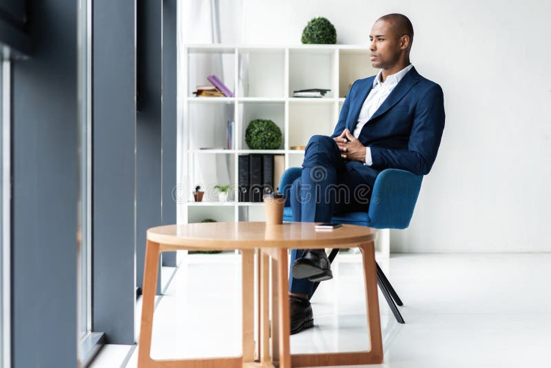 Homem de negócio executivo afro-americano alegre considerável no escritório do espaço de trabalho