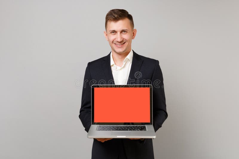 Homem de negócio novo de sorriso no terno preto clássico, computador do PC do portátil da terra arrendada da camisa com a tela va fotos de stock Homem de negócio novo de sorriso no terno preto clássico, computador do PC do portátil da terra arrendada da camisa com a tela va fotos de stock