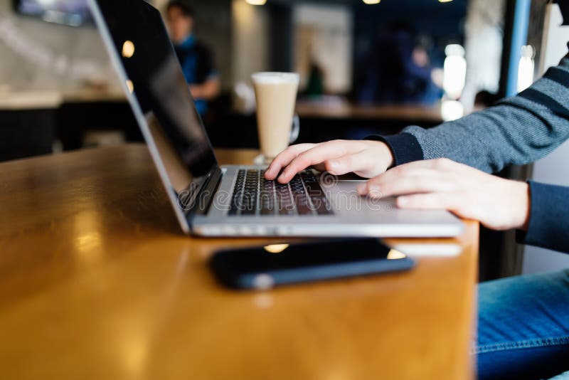 Homem de negócio ocasional que trabalha no laptop com livro, caderno, o smartphone móvel e a xícara de café na tabela na cafetari foto de stock Homem de negócio ocasional que trabalha no laptop com livro, caderno, o smartphone móvel e a xícara de café na tabela na cafetari foto de stock