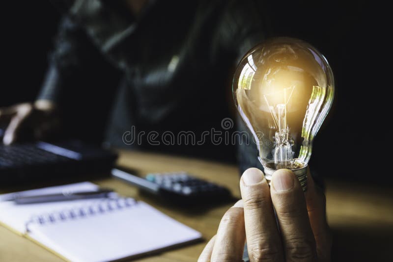 Homem de negócio que guarda a ampola na mesa no escritório e que usa o computador em financeiro, explicando, energia, conceito da ilustração royalty free Homem de negócio que guarda a ampola na mesa no escritório e que usa o computador em financeiro, explicando, energia, conceito da ilustração royalty free