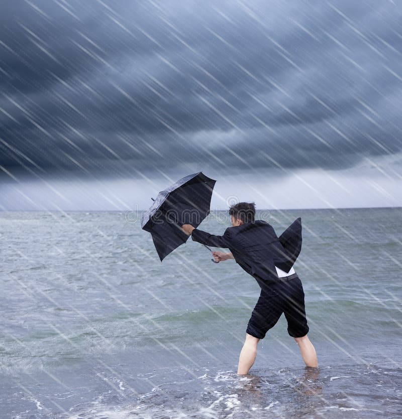 Homem de negócio que guarda um guarda-chuva para resistir a tempestade