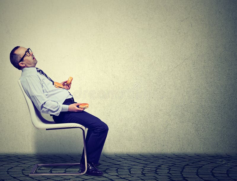 Homem de negócio que sente cansado e sonolento após ter comido hamburgueres demais para o almoço fotos de stock Homem de negócio que sente cansado e sonolento após ter comido hamburgueres demais para o almoço fotos de stock