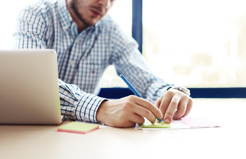 Homem de negócio que trabalha no escritório com portátil e nos originais em sua mesa fotografia de stock royalty free Homem de negócio que trabalha no escritório com portátil e nos originais em sua mesa fotografia de stock royalty free