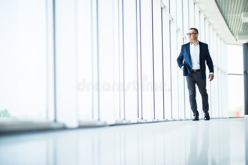 Homem de negócio superior considerável e bem sucedido que anda no interior moderno do escritório imagens de stock Homem de negócio superior considerável e bem sucedido que anda no interior moderno do escritório imagens de stock