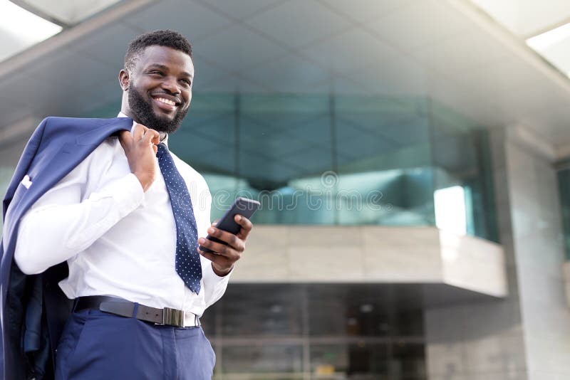 Homem de negócios africano novo que guarda seu telefone ao estar completamente da alegria fotos de stock Homem de negócios africano novo que guarda seu telefone ao estar completamente da alegria fotos de stock