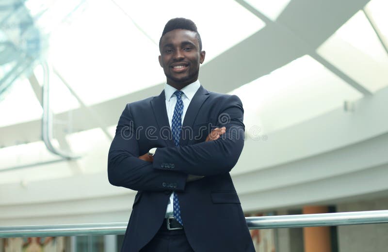 Homem de negócios afro-americano bem sucedido do homem de negócios que está no escritório foto de stock Homem de negócios afro-americano bem sucedido do homem de negócios que está no escritório foto de stock
