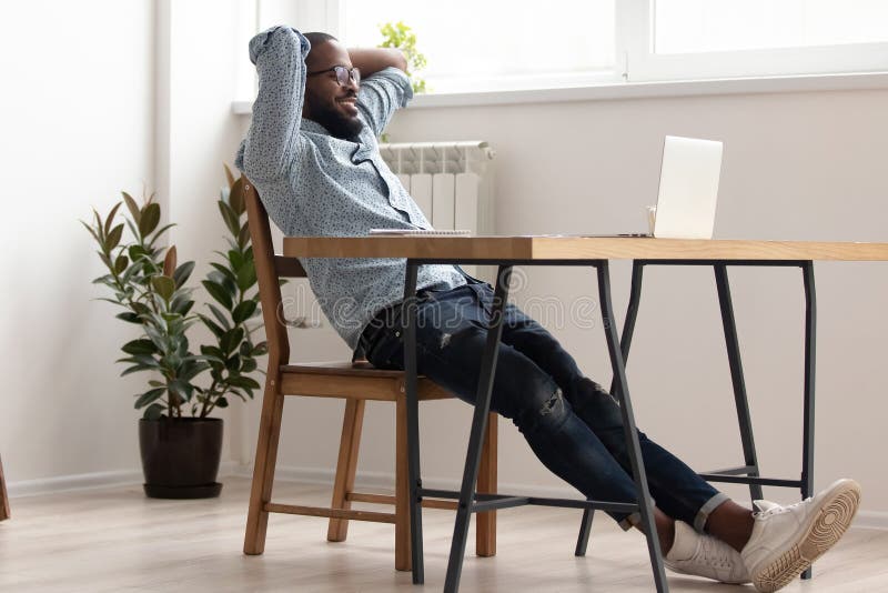 Homem de negócios afro-americano relaxado que refrigera no trabalho terminado sala do escritório
