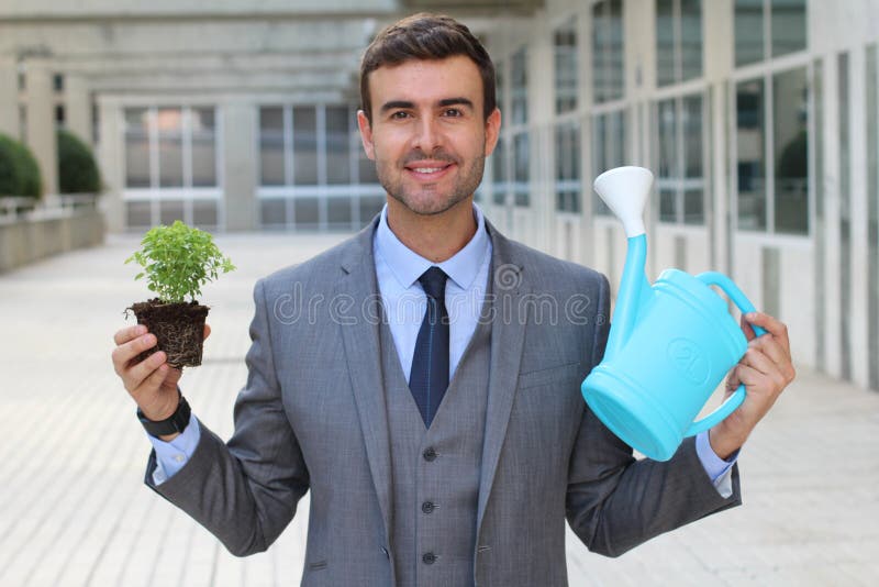 Homem de negócios alegre que toma cuidados adequados de uma planta imagens de stock royalty free Homem de negócios alegre que toma cuidados adequados de uma planta imagens de stock royalty free