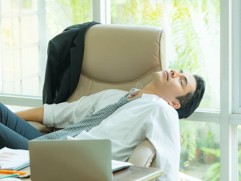 Homem de negócios asiático novo cansado e que dorme após o informati do achado fotografia de stock Homem de negócios asiático novo cansado e que dorme após o informati do achado fotografia de stock