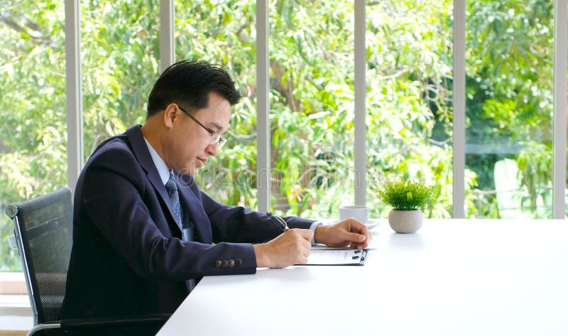 Homem de negócios asiático superior que trabalha no documento em sua mesa de escritório, executivos, conceito do estilo de vida d imagem de stock royalty free Homem de negócios asiático superior que trabalha no documento em sua mesa de escritório, executivos, conceito do estilo de vida d imagem de stock royalty free