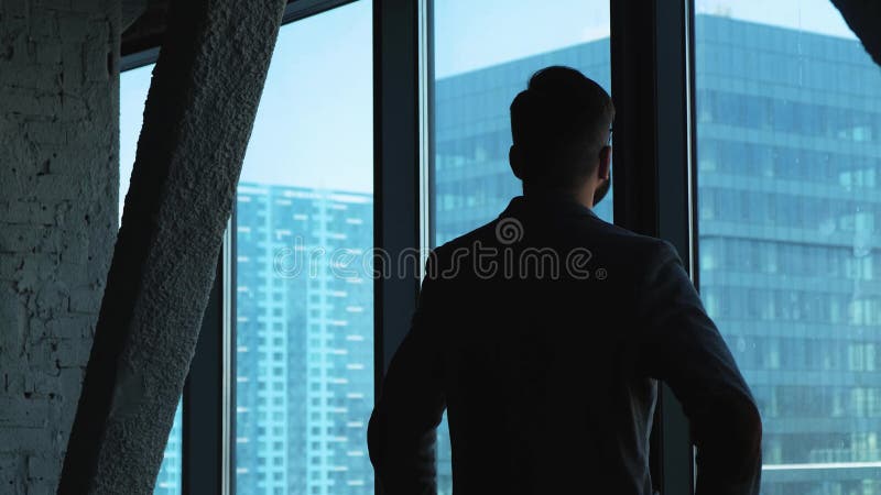 Homem de negócios bem sucedido novo que olha para fora a janela na baixa Edifício elevado do negócio Escritório no estilo do sótã