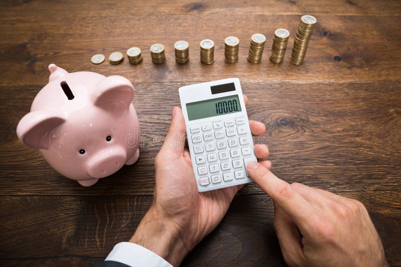 Homem de negócios With Coins And Piggybank que usa a calculadora fotos de stock Homem de negócios With Coins And Piggybank que usa a calculadora fotos de stock