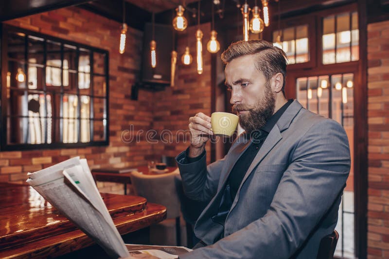 Homem de negócios considerável novo que lê um jornal imagens de stock royalty free Homem de negócios considerável novo que lê um jornal imagens de stock royalty free