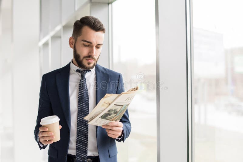 Homem de negócios considerável Reading Newspaper pela janela imagem de stock royalty free Homem de negócios considerável Reading Newspaper pela janela imagem de stock royalty free