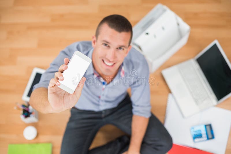 Homem de negócios criativo novo que mostra seu smartphone imagens de stock royalty free Homem de negócios criativo novo que mostra seu smartphone imagens de stock royalty free