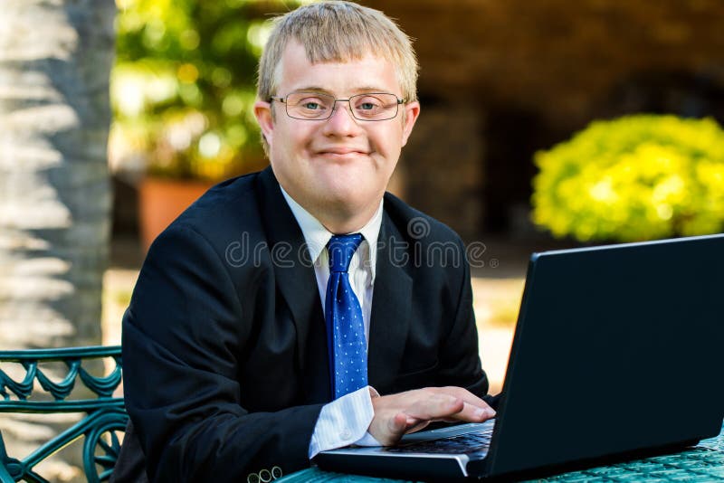 Homem de negócios deficiente novo que trabalha com portátil imagem de stock Homem de negócios deficiente novo que trabalha com portátil imagem de stock