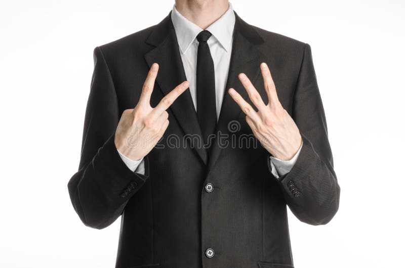 Homem de negócios e assunto do gesto: um homem em um terno preto com um laço que mostra um sinal com seu iso do sinal da mão esqu foto de stock Homem de negócios e assunto do gesto: um homem em um terno preto com um laço que mostra um sinal com seu iso do sinal da mão esqu foto de stock