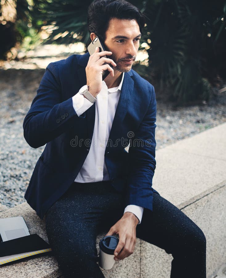 Homem de negócios elegante pensativo que usa o smartphone contemporâneo ao tomar o resto durante o dia do trabalho Guardando as m fotografia de stock royalty free Homem de negócios elegante pensativo que usa o smartphone contemporâneo ao tomar o resto durante o dia do trabalho Guardando as m fotografia de stock royalty free