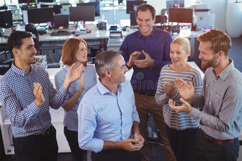Homem de negócios feliz que está pelos colegas que aplaudem imagens de stock royalty free Homem de negócios feliz que está pelos colegas que aplaudem imagens de stock royalty free