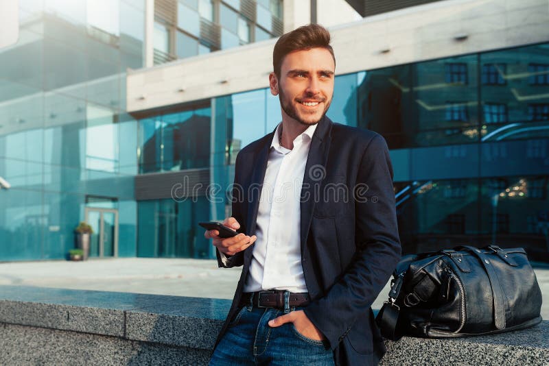 Homem de negócios milenar com um telefone celular em suas mãos imagem de stock royalty free Homem de negócios milenar com um telefone celular em suas mãos imagem de stock royalty free