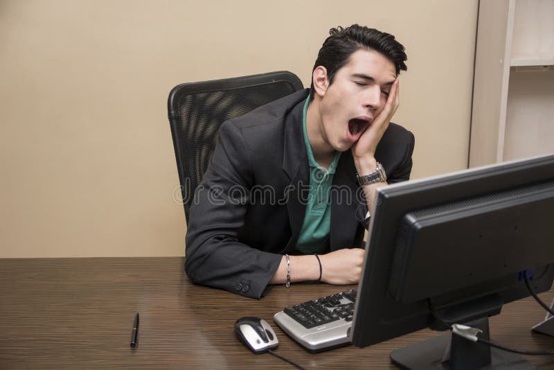 Homem de negócios novo furado cansado que senta-se no escritório foto de stock royalty free Homem de negócios novo furado cansado que senta-se no escritório foto de stock royalty free