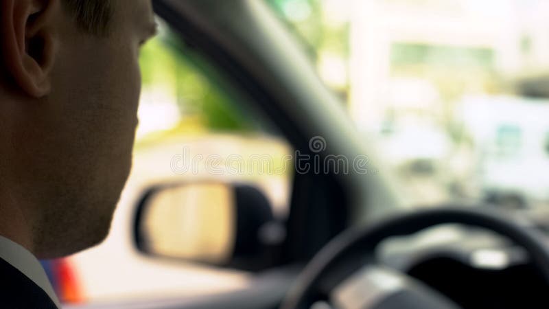 Homem de negócios novo que conduz o carro no tráfego de cidade, indo à reunião do escritório, fim acima fotografia de stock royalty free Homem de negócios novo que conduz o carro no tráfego de cidade, indo à reunião do escritório, fim acima fotografia de stock royalty free