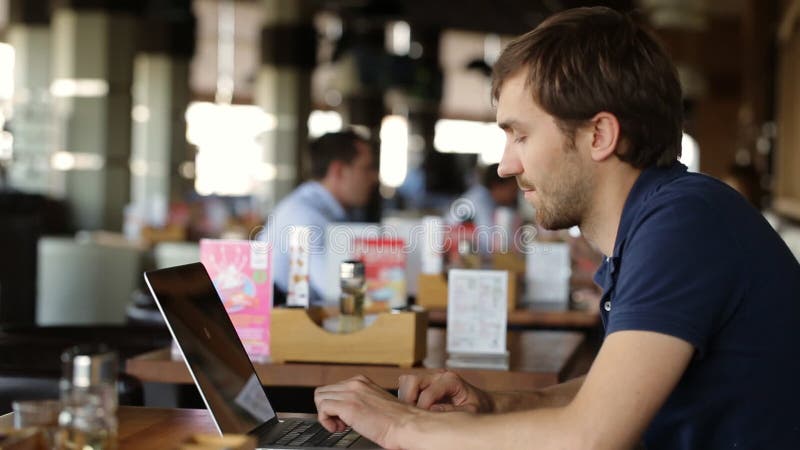 Homem de negócios novo que usa-se no portátil no café