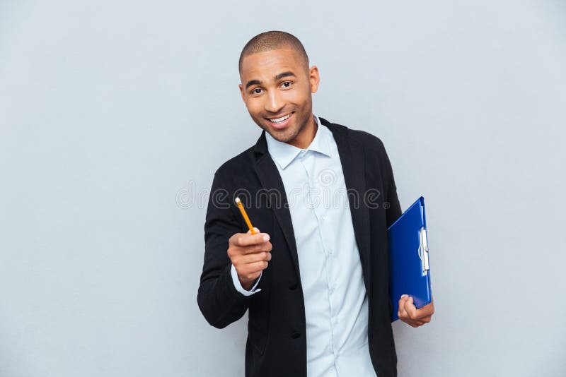 Homem de negócios novo seguro alegre que guarda a prancheta fotografia de stock royalty free Homem de negócios novo seguro alegre que guarda a prancheta fotografia de stock royalty free