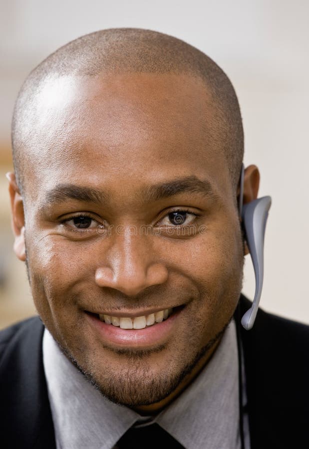 Homem de negócios que desgasta auriculares sem fio imagens de stock Homem de negócios que desgasta auriculares sem fio imagens de stock