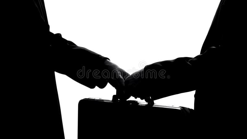 Homem de negócios que dá a mala de viagem ao sócio, economia subterrânea, negócio ilegal, subôrno fotografia de stock Homem de negócios que dá a mala de viagem ao sócio, economia subterrânea, negócio ilegal, subôrno fotografia de stock
