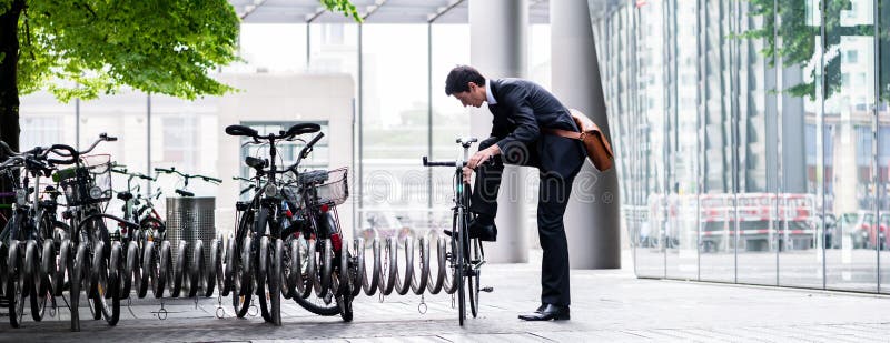 Homem de negócios que estaciona sua bicicleta na cidade