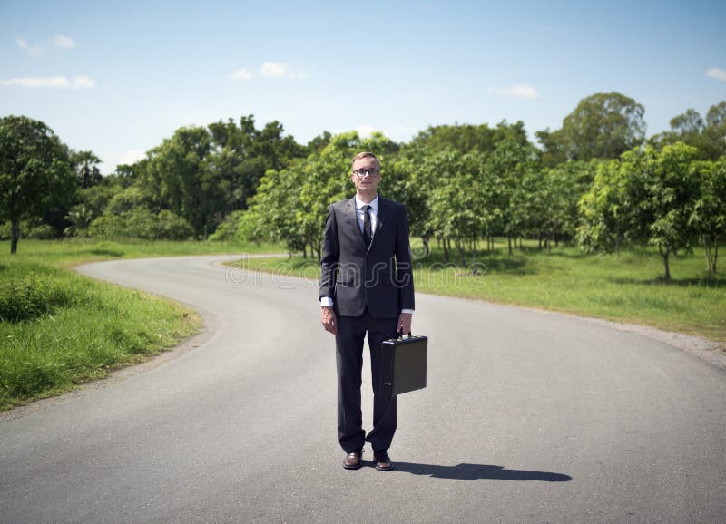 Homem de negócios que está em uma estrada imagens de stock royalty free Homem de negócios que está em uma estrada imagens de stock royalty free