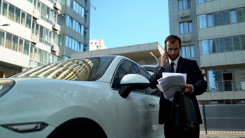 Homem de negócios que fala no telefone perto do carro, resolvendo introduções financeiras da empresa imagens de stock royalty free Homem de negócios que fala no telefone perto do carro, resolvendo introduções financeiras da empresa imagens de stock royalty free