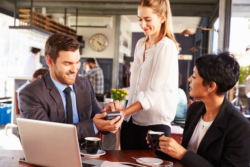 Homem de negócios que faz o pagamento com cartão de crédito em um café imagens de stock Homem de negócios que faz o pagamento com cartão de crédito em um café imagens de stock