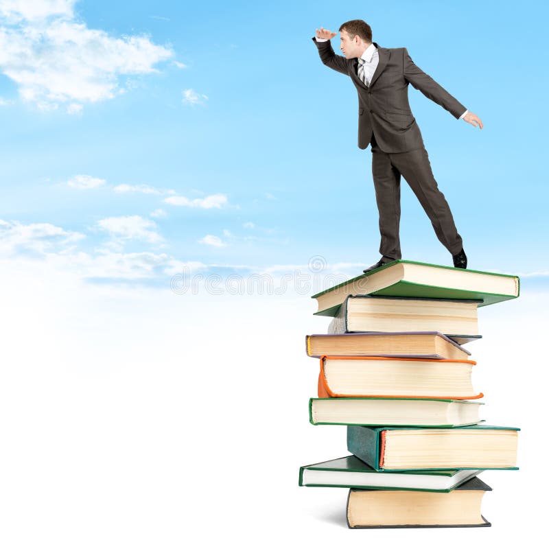 Homem de negócios que fica na pilha dos livros entre nuvens imagem de stock royalty free Homem de negócios que fica na pilha dos livros entre nuvens imagem de stock royalty free