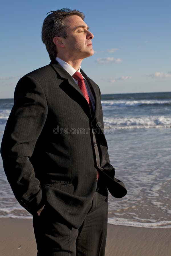 Businessman meditating on the beach about his life, his plans, feeling the wind blowing on his face. Businessman meditating on the beach about his life, his plans, feeling the wind blowing on his face