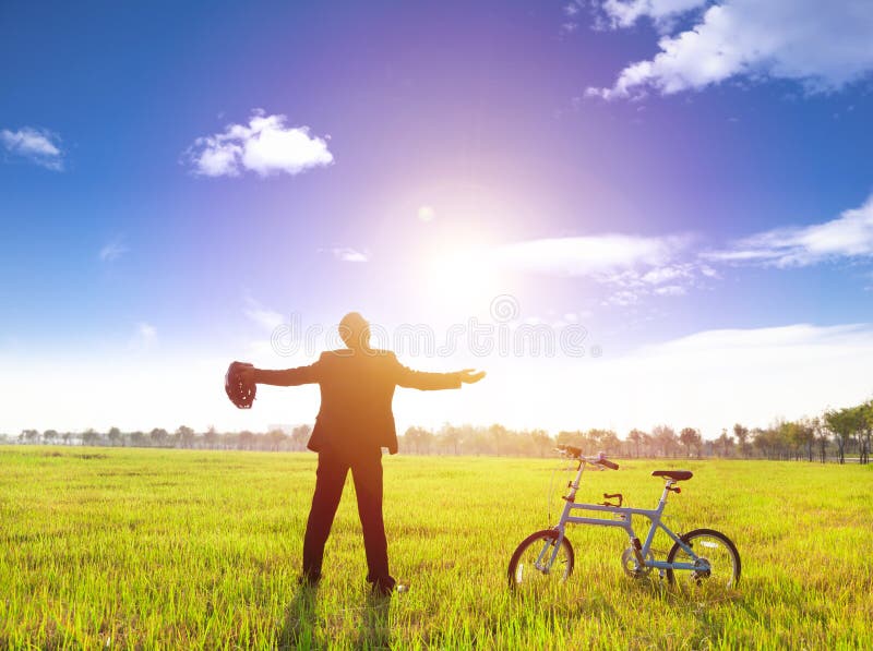 Homem de negócios que relaxa na terra e no sol verdes com bicicleta fotografia de stock royalty free Homem de negócios que relaxa na terra e no sol verdes com bicicleta fotografia de stock royalty free
